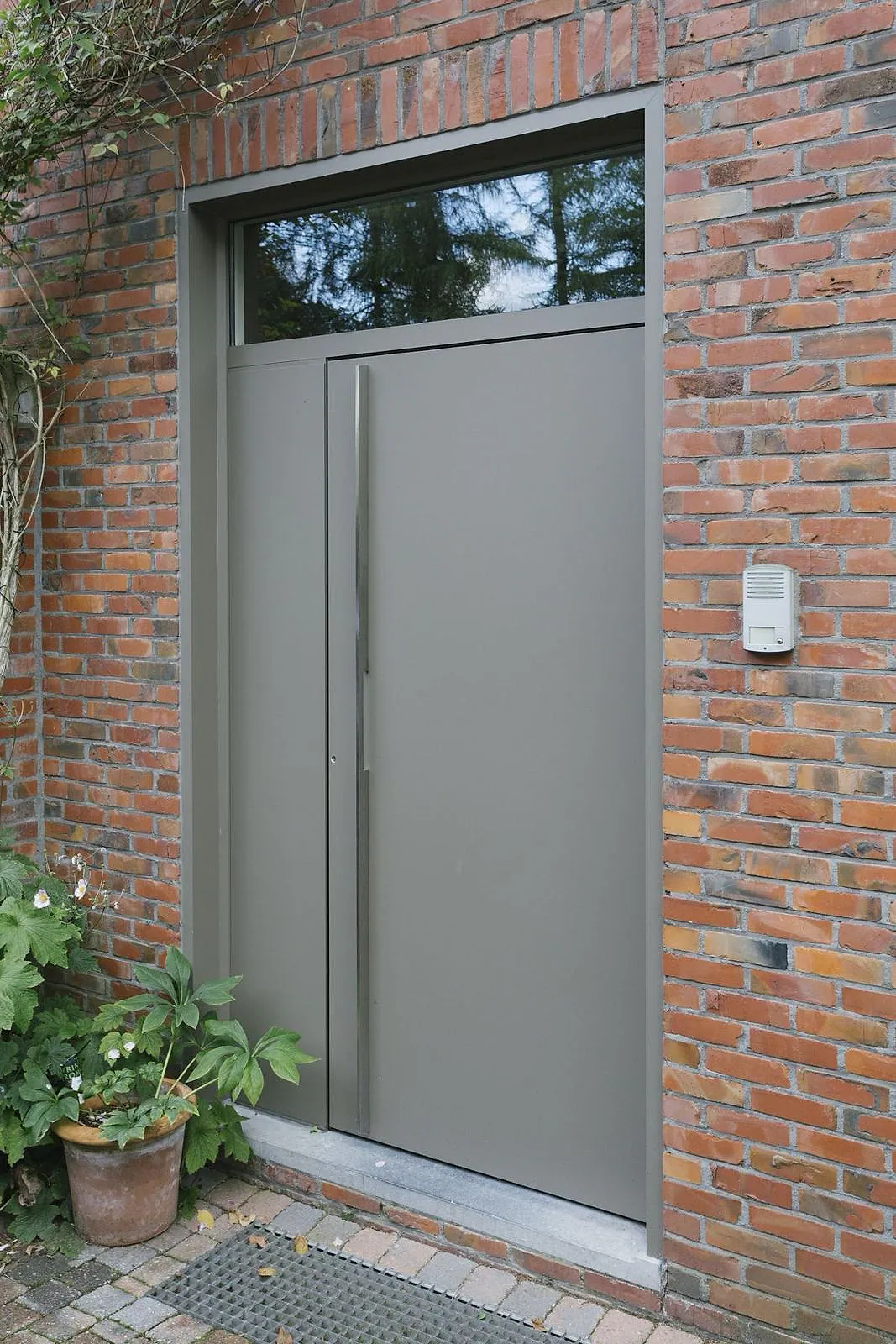 Gray aluminum entry door with a glazed transom in brick façade – aluminum project reference featured on Projects & References | Custom Aluminum Windows